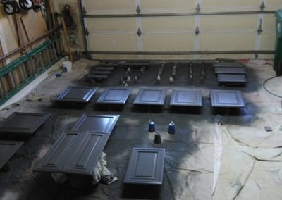An image of kitchen cabinet doors and drawer fronts layed out in a garage for refinishing